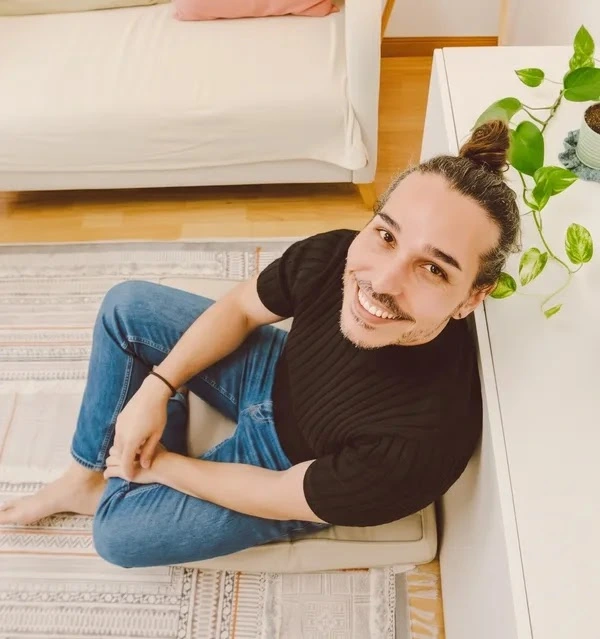 David Pérez, terapeuta Gestalt en Barcelona especializado en hombres GBTIAQ+, sonriendo en su espacio de consulta.